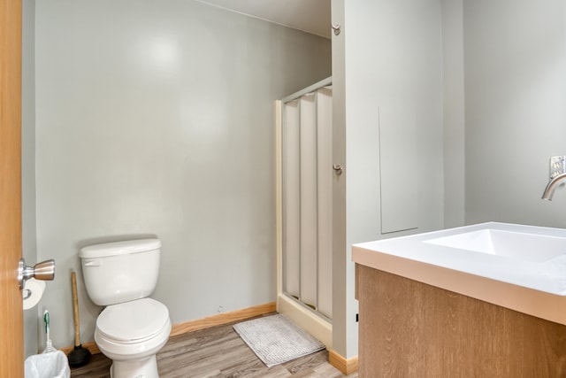 bathroom featuring hardwood / wood-style flooring, vanity, toilet, and a shower with shower door