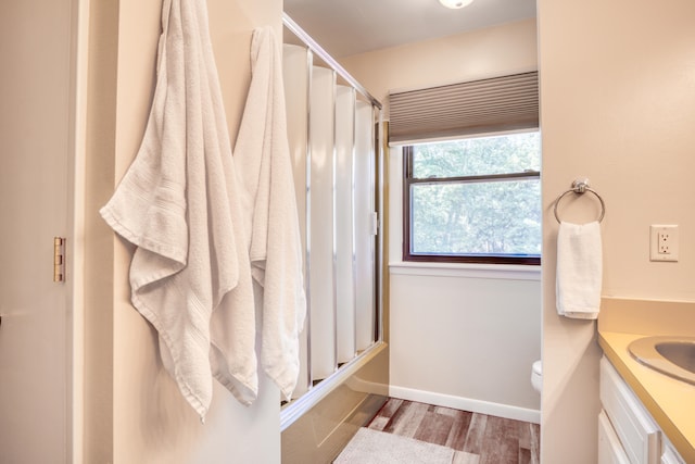 full bathroom featuring vanity, toilet, wood-type flooring, and bath / shower combo with glass door