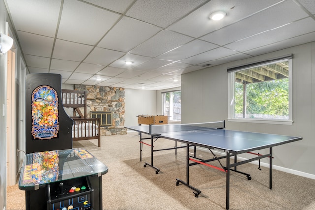 playroom featuring a stone fireplace, a drop ceiling, and carpet floors