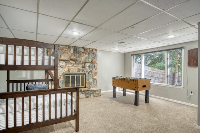 rec room with carpet flooring, a fireplace, and a drop ceiling