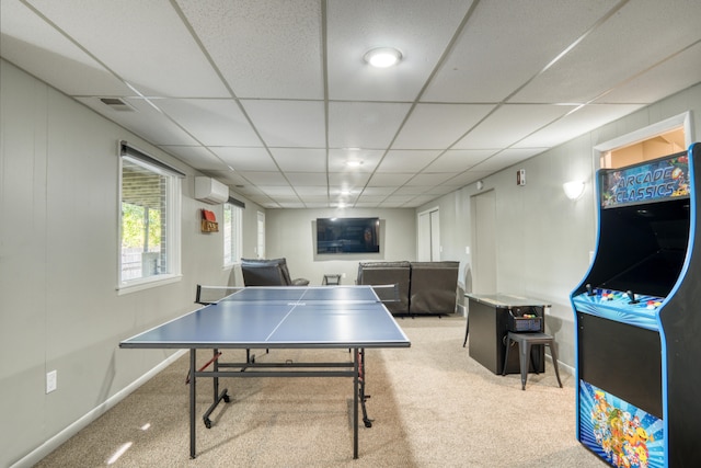 recreation room with carpet floors, a wall unit AC, and a drop ceiling