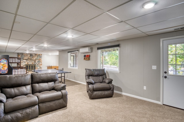 living room with a wall unit AC, a stone fireplace, and carpet