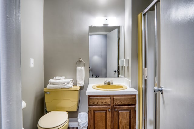 bathroom with vanity, toilet, and a shower with door