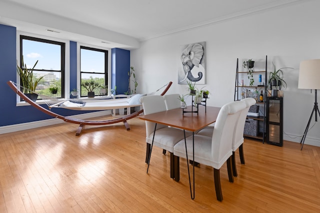 dining space featuring light hardwood / wood-style floors and ornamental molding