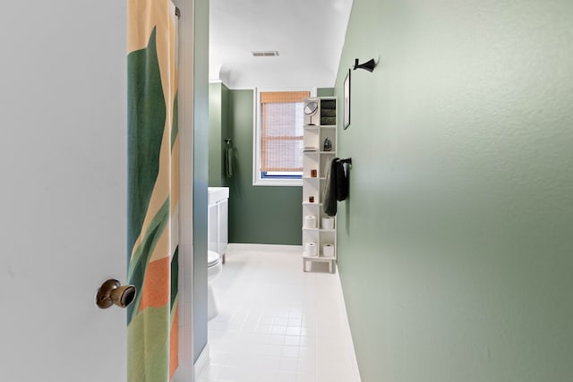 hall featuring light tile patterned flooring and vaulted ceiling