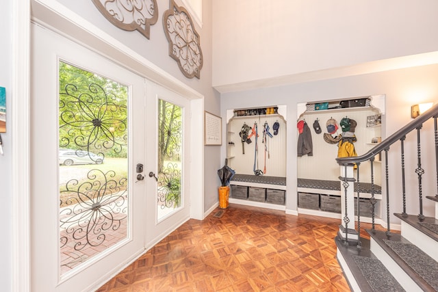 mudroom with french doors, a towering ceiling, and baseboards