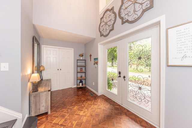 doorway with a towering ceiling, visible vents, baseboards, and french doors