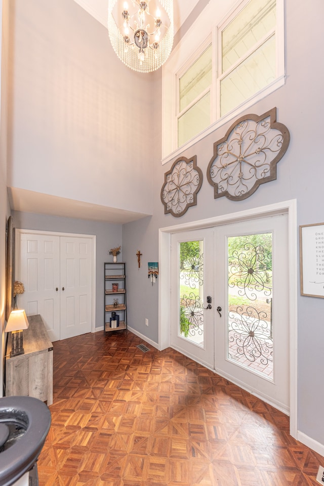 foyer entrance with french doors, baseboards, a high ceiling, and an inviting chandelier