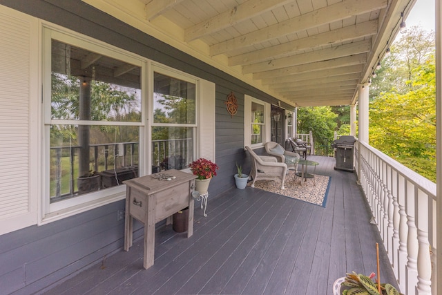 wooden deck featuring covered porch and a grill