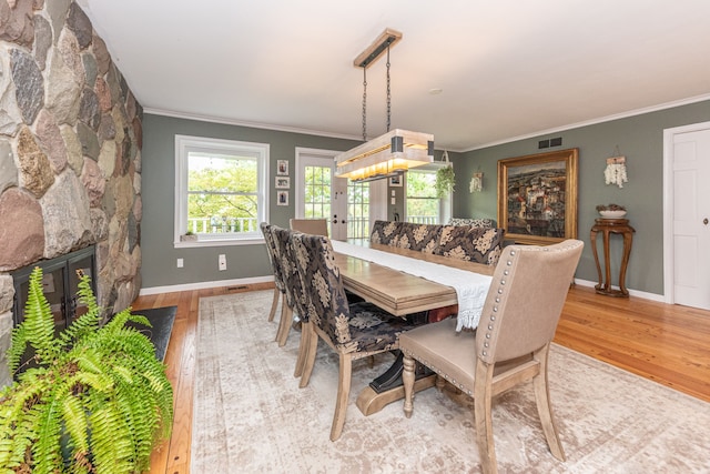 dining room featuring baseboards, visible vents, ornamental molding, wood finished floors, and a fireplace