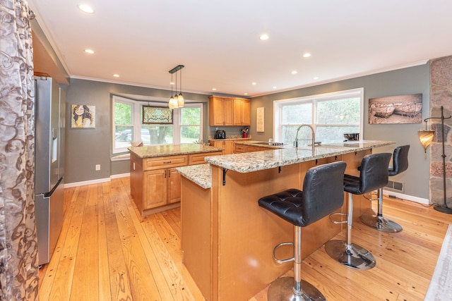 kitchen featuring light wood finished floors, a large island, crown molding, and stainless steel fridge