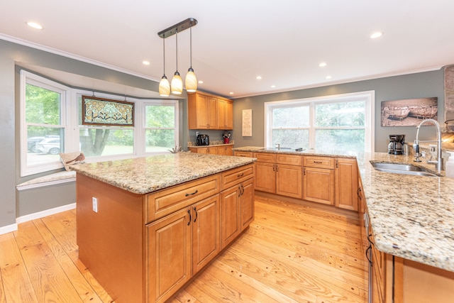 kitchen with ornamental molding, light stone counters, and a sink