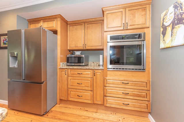 kitchen featuring baseboards, ornamental molding, light stone countertops, stainless steel appliances, and light wood-style floors