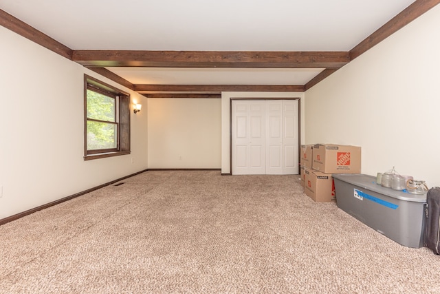 unfurnished bedroom featuring carpet, visible vents, baseboards, and beam ceiling