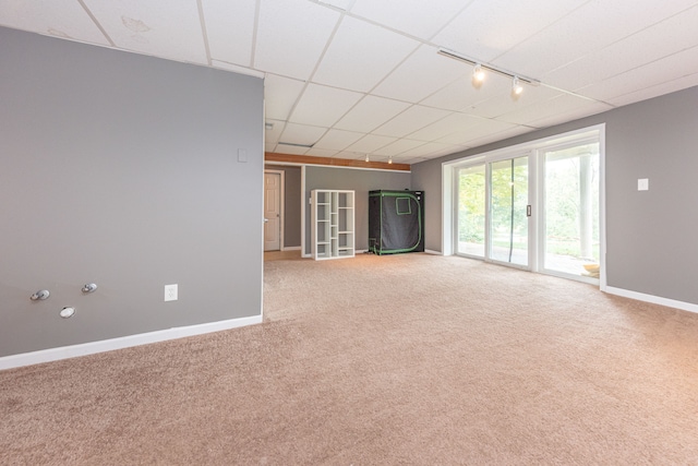 empty room with carpet floors, a paneled ceiling, rail lighting, and baseboards