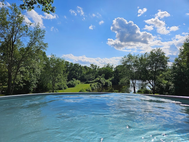 view of swimming pool featuring a view of trees