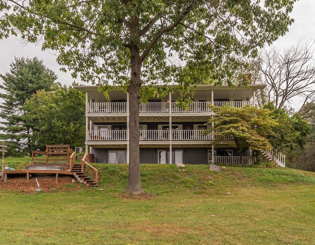 rear view of house featuring a chimney, stairway, a deck, and a lawn