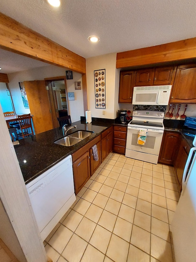 kitchen featuring a textured ceiling, sink, light tile patterned floors, and white appliances