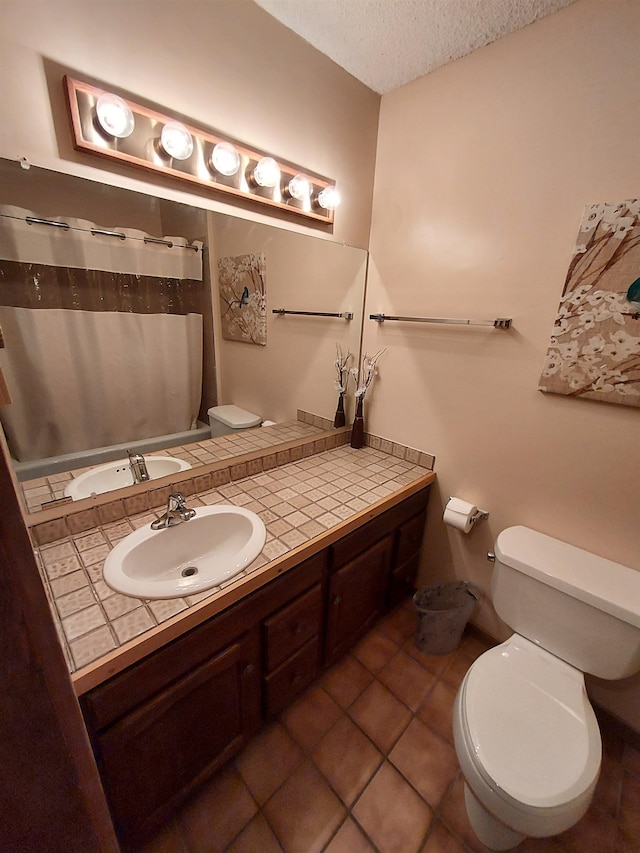 bathroom with tile patterned floors, vanity, a textured ceiling, toilet, and curtained shower