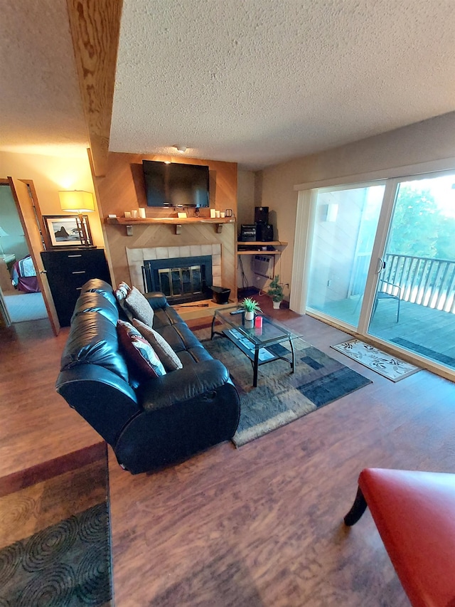 living room with a fireplace, wood-type flooring, a textured ceiling, and beamed ceiling