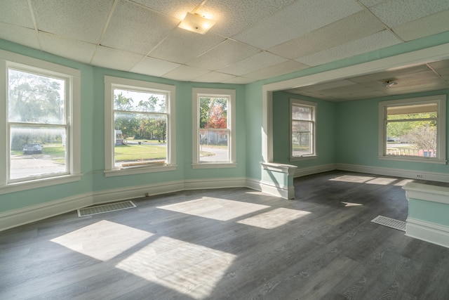 unfurnished room with a paneled ceiling and dark hardwood / wood-style floors