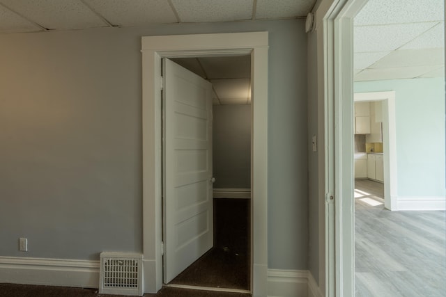 corridor with wood-type flooring and a drop ceiling