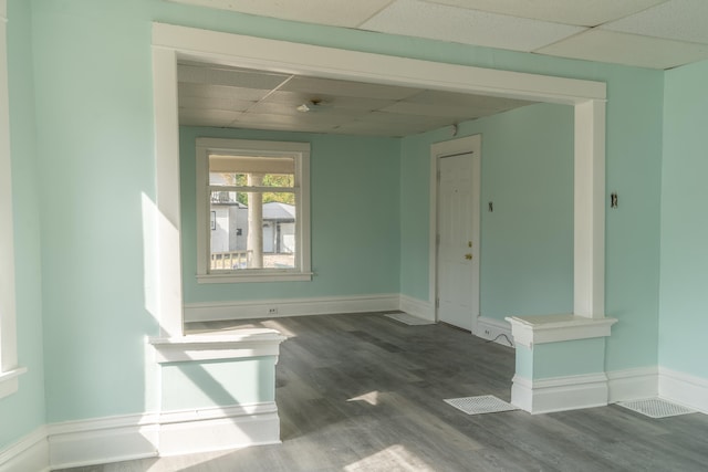 empty room with a drop ceiling and hardwood / wood-style floors