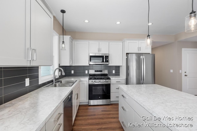 kitchen featuring appliances with stainless steel finishes, white cabinets, light countertops, and a sink