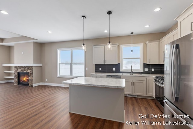 kitchen featuring pendant lighting, stainless steel appliances, light countertops, open floor plan, and white cabinetry