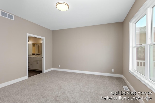 unfurnished bedroom with carpet floors, ensuite bath, visible vents, and baseboards