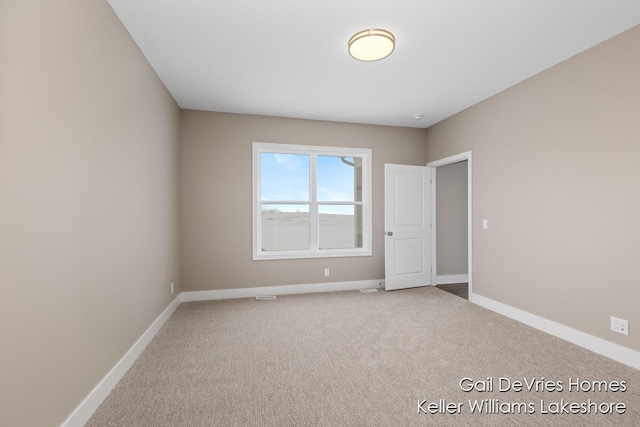 unfurnished room featuring carpet and baseboards