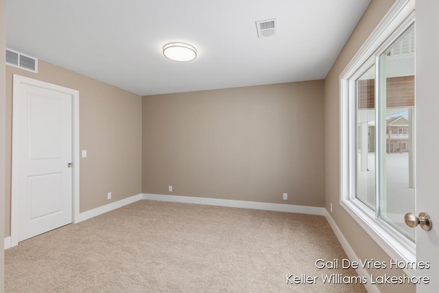 spare room with light carpet, visible vents, and baseboards