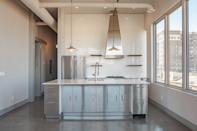 kitchen featuring sink, hanging light fixtures, light stone countertops, high quality fridge, and tasteful backsplash