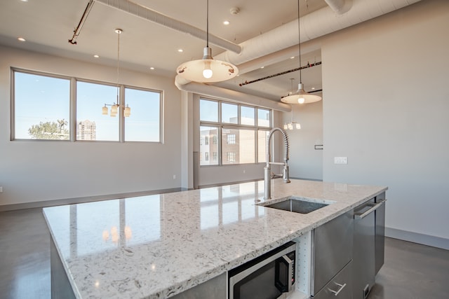 kitchen featuring light stone countertops, appliances with stainless steel finishes, sink, decorative light fixtures, and a large island