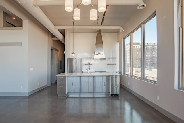 kitchen with stainless steel fridge, backsplash, a spacious island, sink, and hanging light fixtures