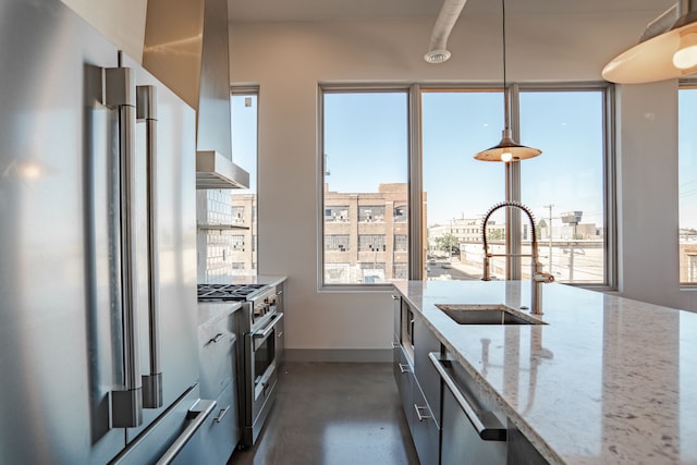 kitchen featuring high quality appliances, sink, light stone countertops, and decorative light fixtures