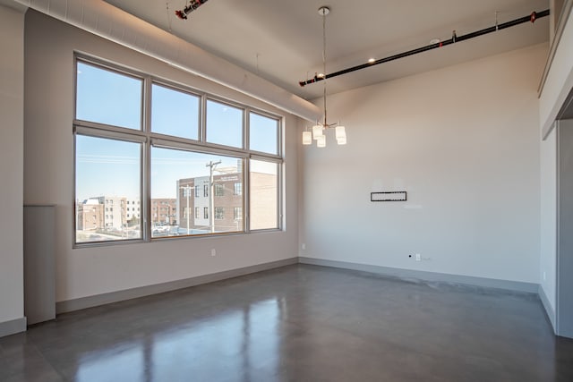 empty room featuring a wealth of natural light and a chandelier