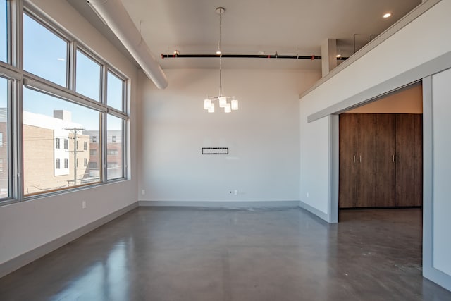 unfurnished dining area with a chandelier, a towering ceiling, and a healthy amount of sunlight