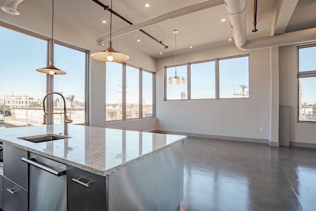 kitchen featuring sink, plenty of natural light, hanging light fixtures, and an island with sink