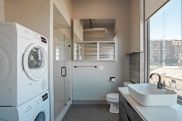 bathroom with stacked washer / dryer, concrete flooring, an enclosed shower, toilet, and vanity