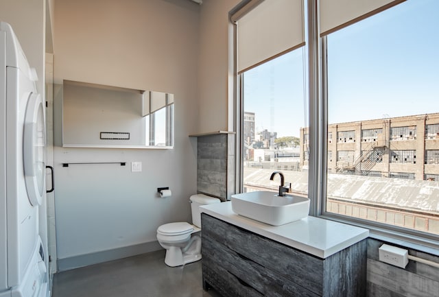 bathroom featuring concrete flooring, vanity, toilet, and a wealth of natural light