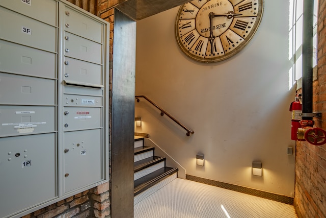 stairway featuring mail boxes and brick wall