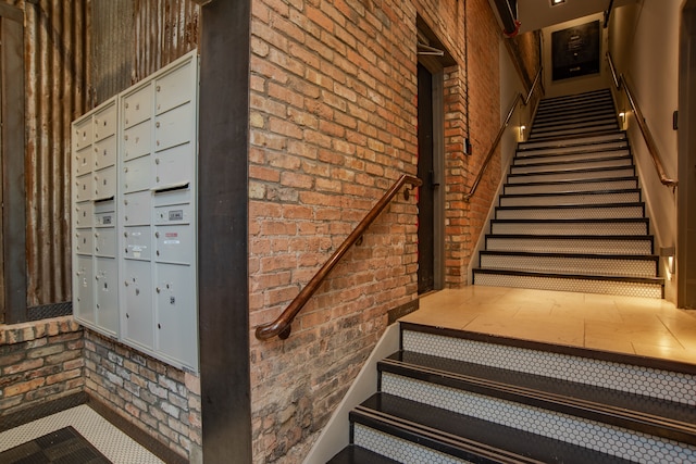 stairs featuring a mail area and brick wall