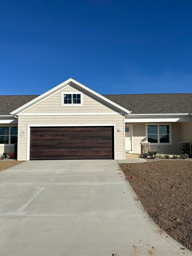 view of front of house with concrete driveway, roof with shingles, and an attached garage