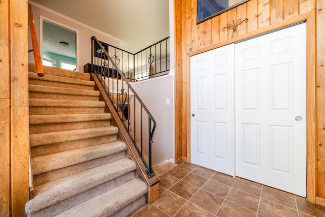 staircase with tile patterned floors and ornamental molding