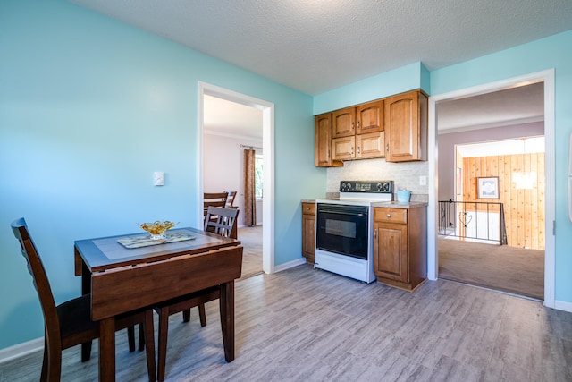 kitchen with white range with electric cooktop, decorative backsplash, light hardwood / wood-style flooring, and a textured ceiling