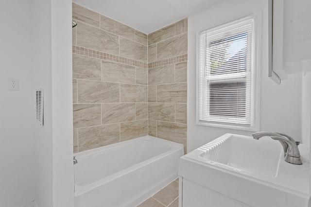 bathroom with tile patterned flooring, tiled shower / bath combo, and sink