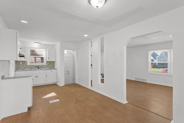 kitchen with white cabinets, backsplash, light hardwood / wood-style floors, and sink