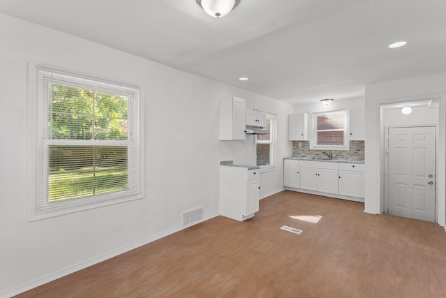 interior space with white cabinets, decorative backsplash, sink, and light hardwood / wood-style flooring