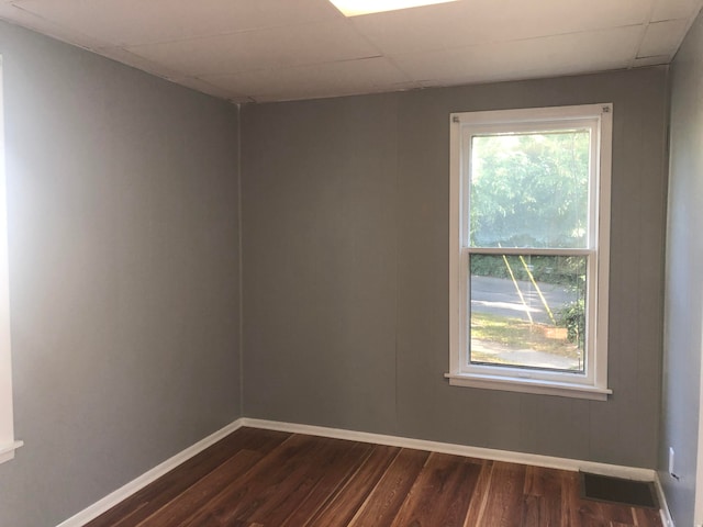 unfurnished room featuring a paneled ceiling and dark hardwood / wood-style floors